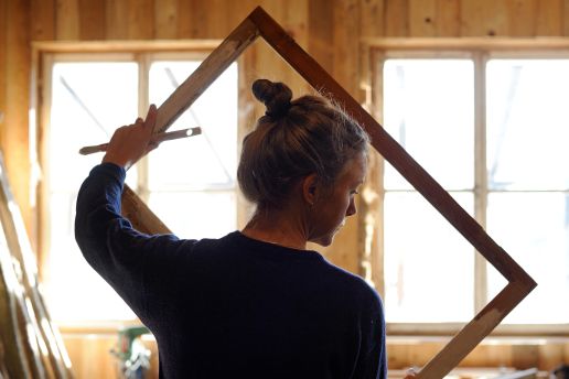 Lina från Väfjällets bygghantverk håller i nytillverkad fönsterram.